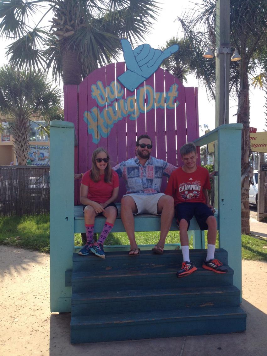 A group of people sitting on a bench in front of a sign