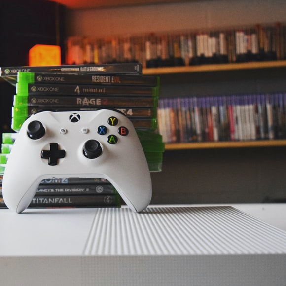 Xbox controller and games for the xbox one with playstation in the background