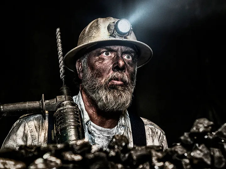 Dirty coal miner stares into the distance