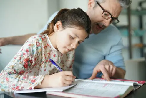 Una niña estudia con la ayuda de su padre. A young girl is studying with the help of her father