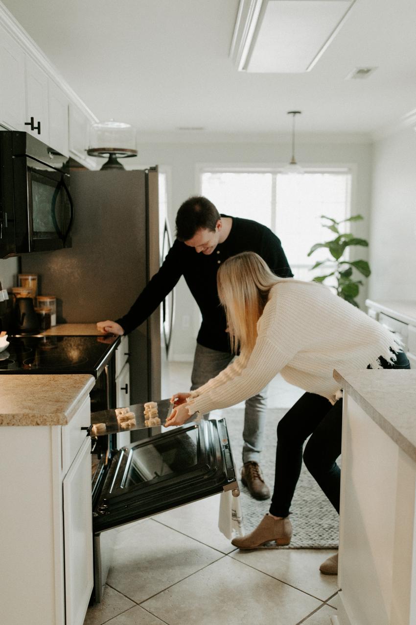 Baking couple baking christmas holiday cookies and putting in the oven