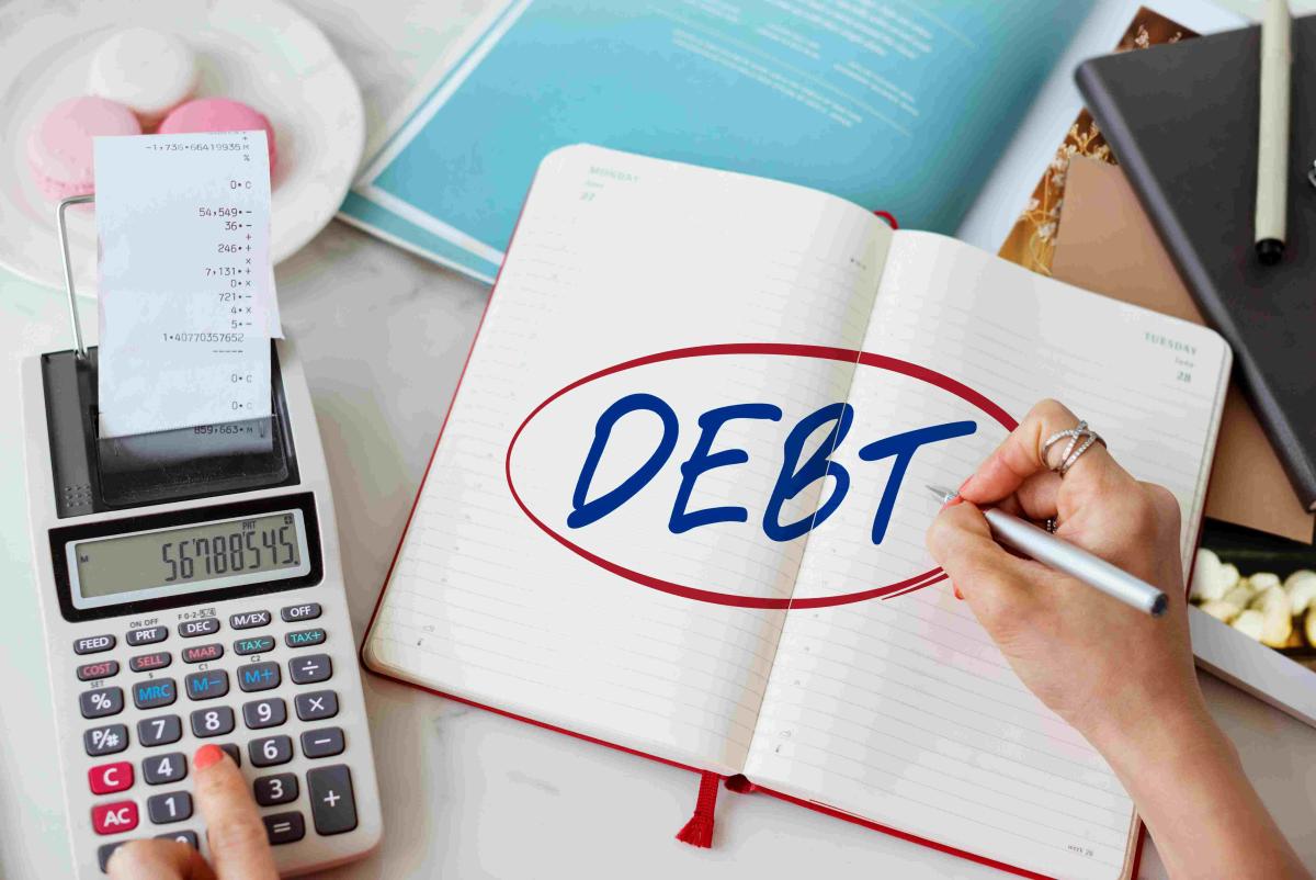 Does Debt Resolution  A worried person sitting at a desk reviewing bills and financial documents, symbolizing the stress of debt, with a calendar and clock in the background representing the time involved in debt resolution.