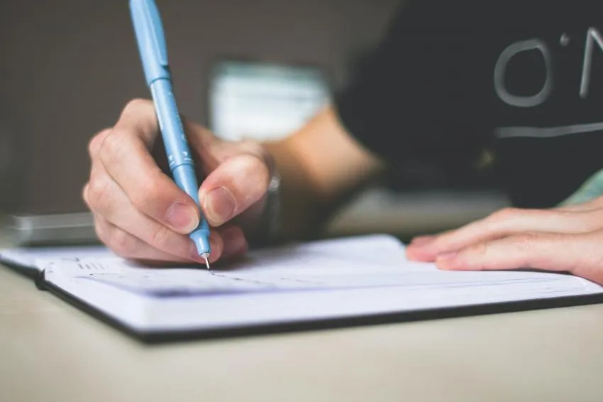 Hand writing in notebook with pen.