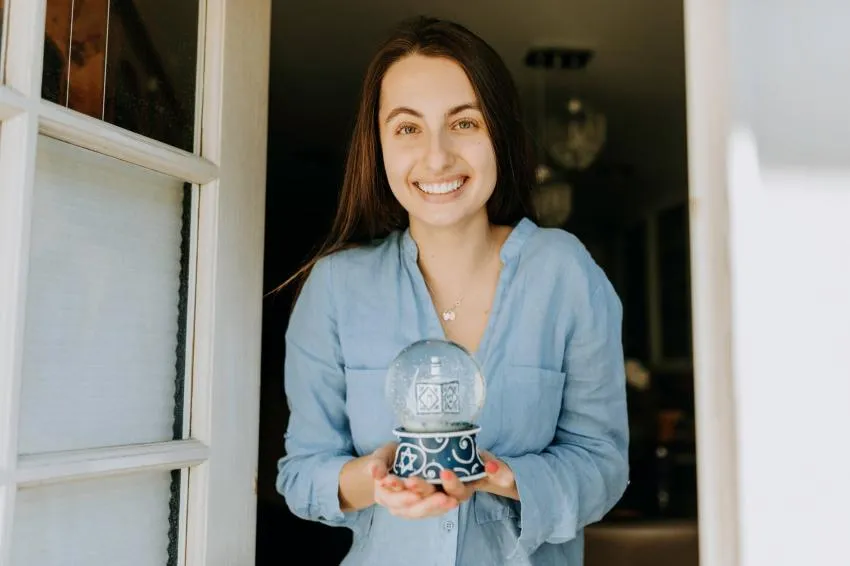 A person holding a snowglobe with a dreidel inside