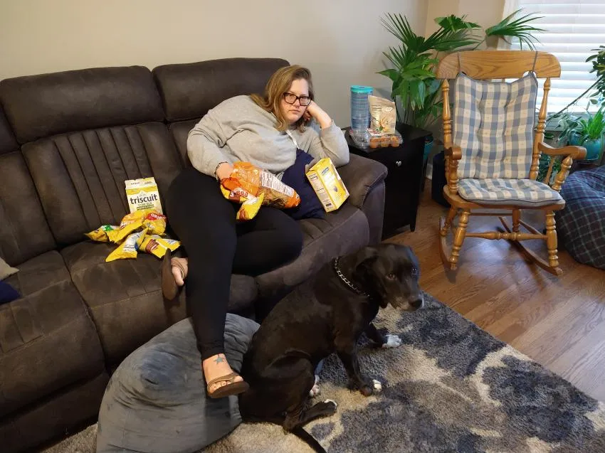 Woman sitting on the couch with alot of snacks