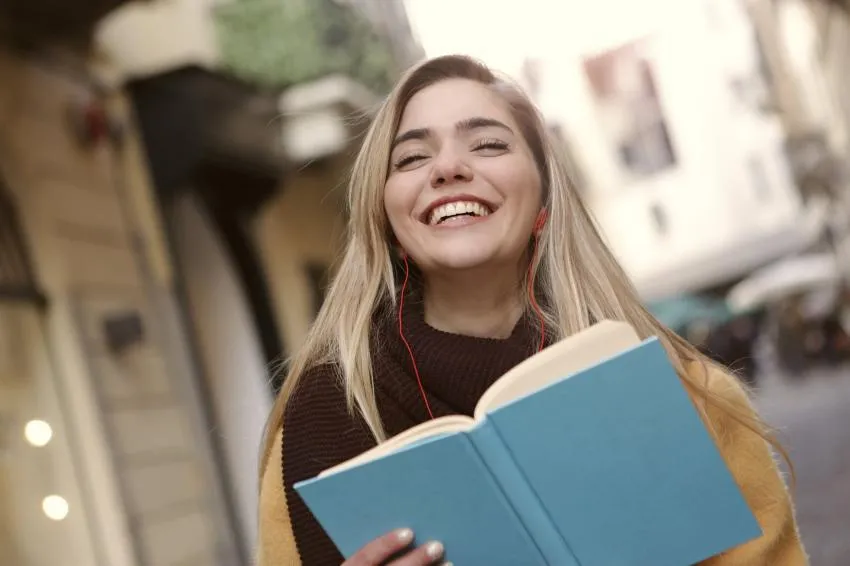 A person smiling holding a book