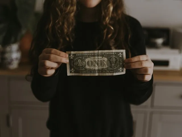 girl holding one dollar