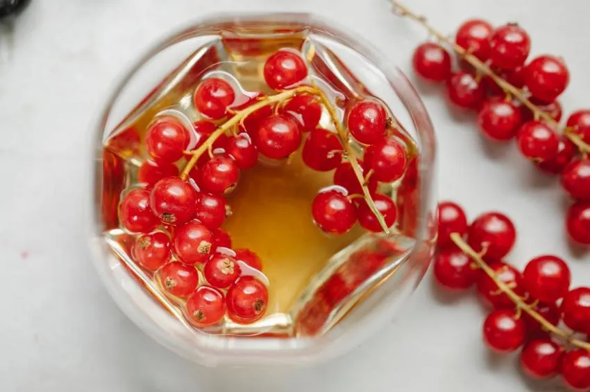 Bebida roja y dorada A drink with berries in it